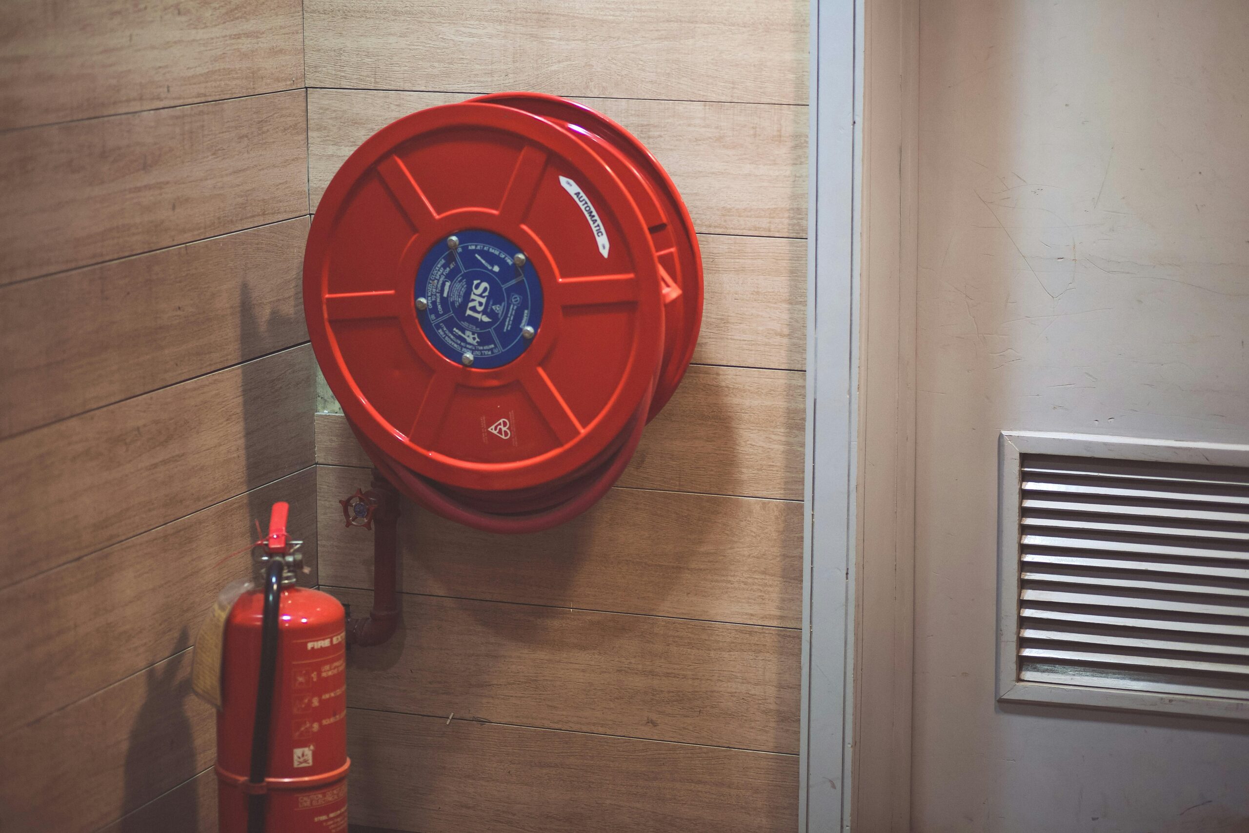 Services Red fire hose reel and extinguisher inside a building corner.