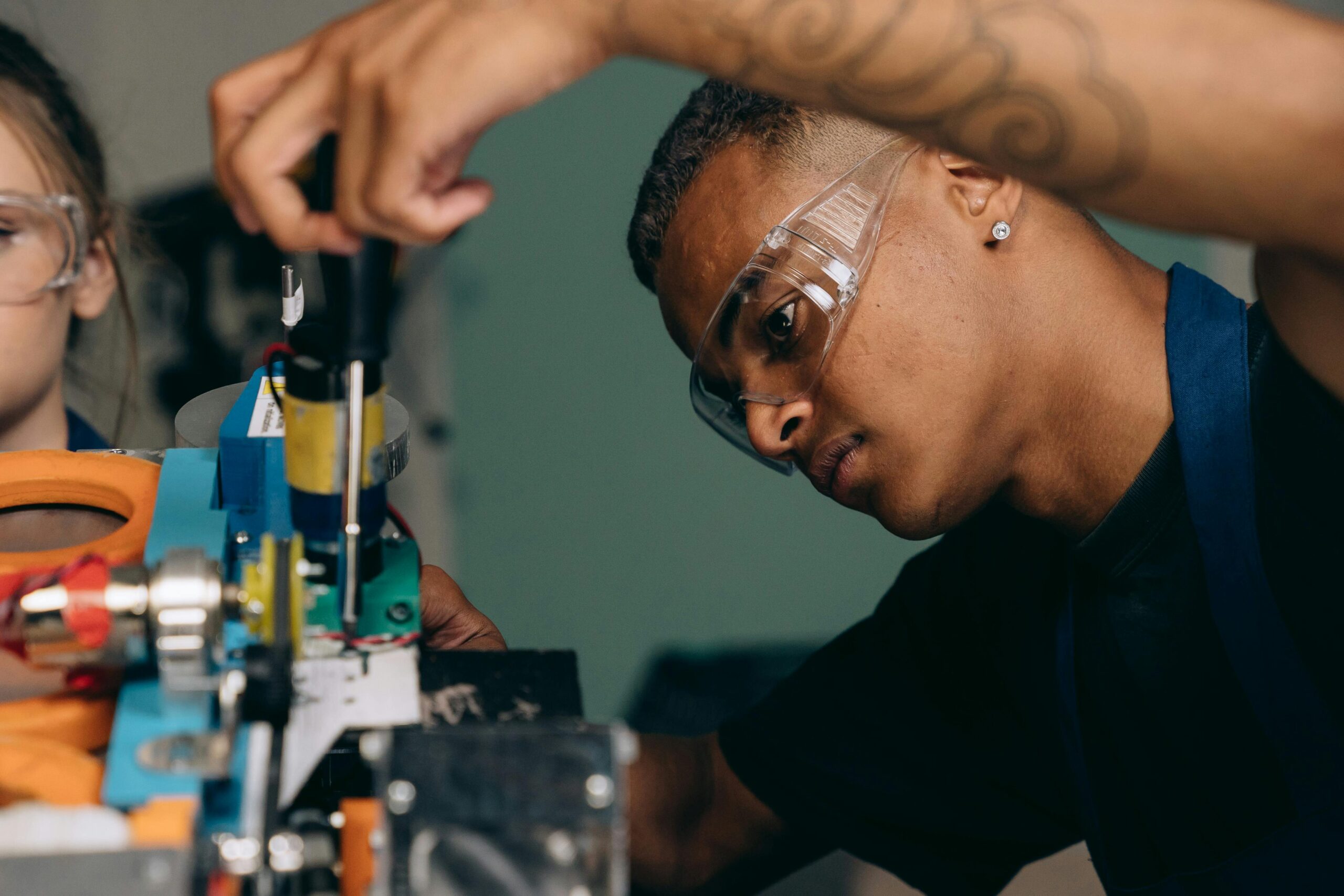 Training & Consultancy Two young technicians focus on electronic equipment assembly in a workshop setting.