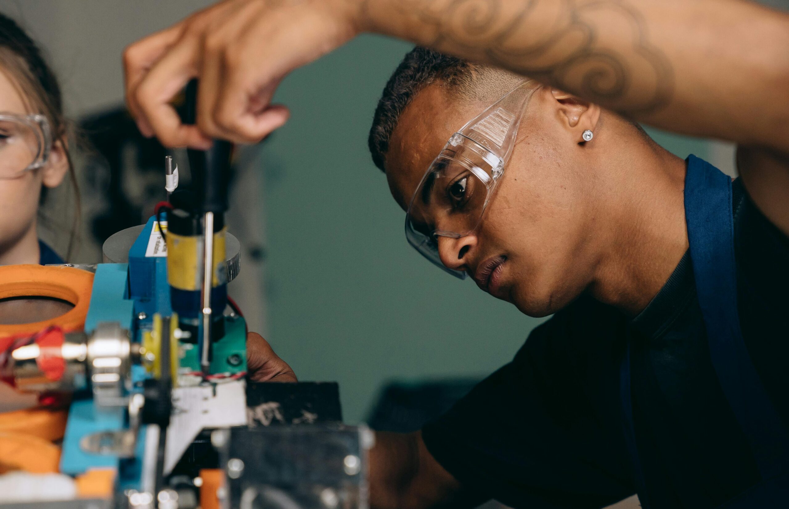 Services Two young technicians focus on electronic equipment assembly in a workshop setting.